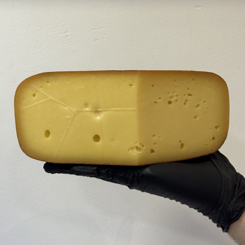 Queso ahumado de leche de vaca elaborado artesanalmente con leche cruda y ahumado tradicionalmente en un ahumadero.
